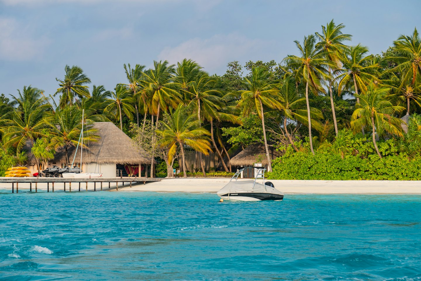 Isla tropical con bungalows, barcos y playa.